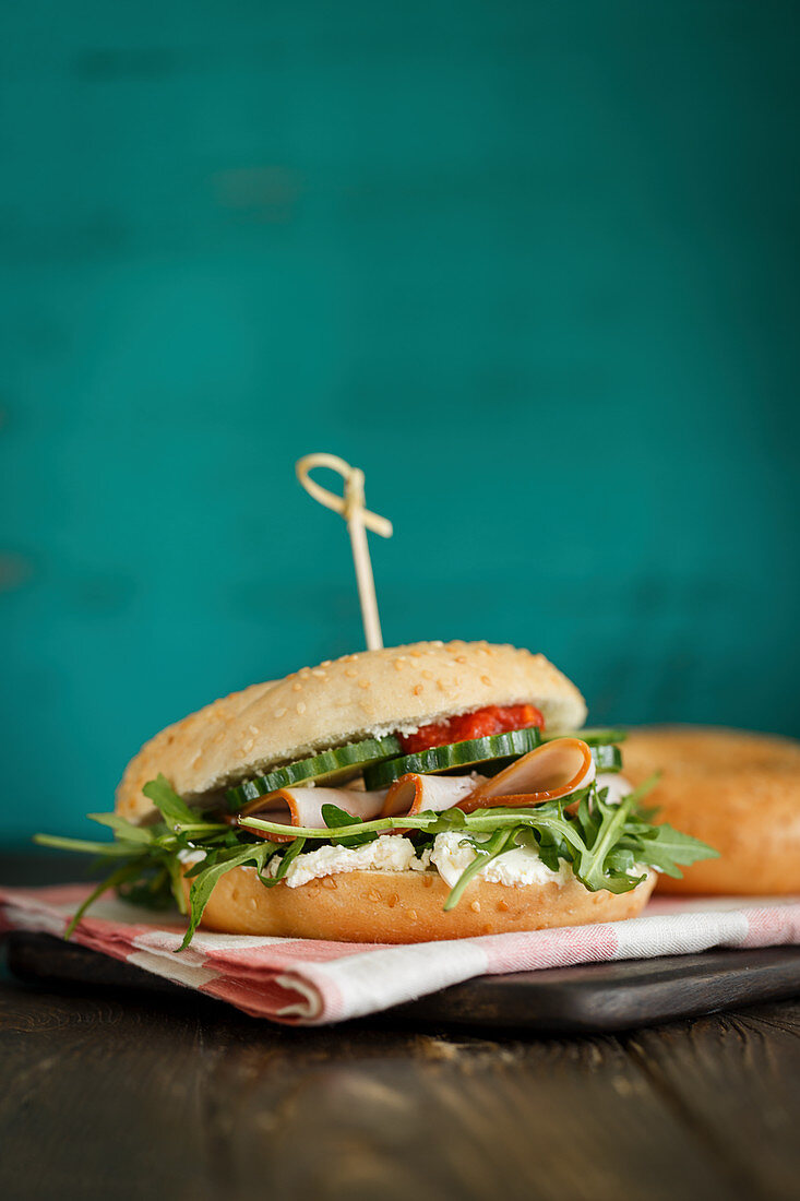 A bagel sandwich with smoked turkey breast, rocket and cucumbers