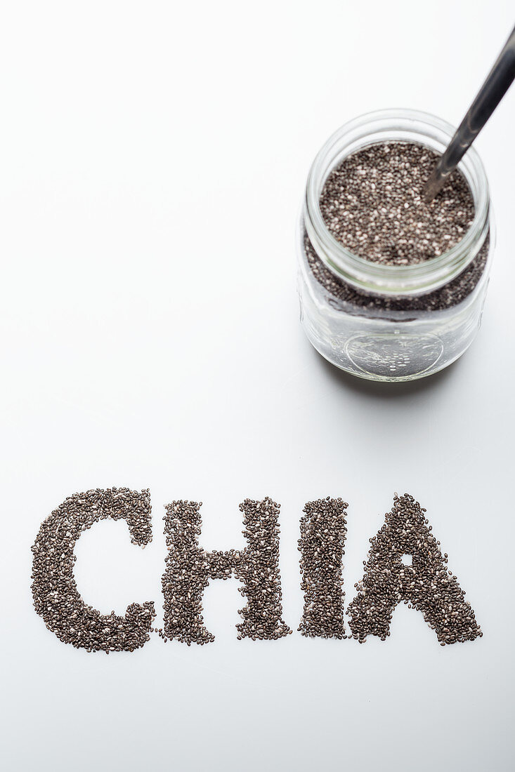 Chia seeds: in a glass jar and lettered against a white background