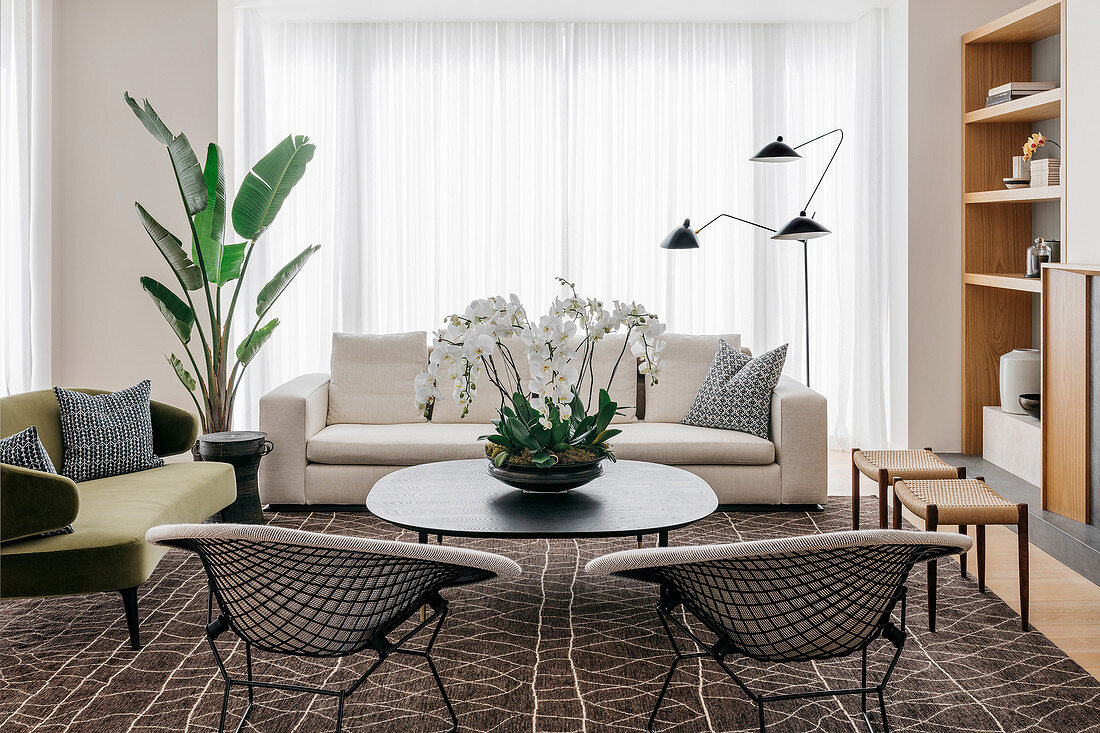 Retro seating and coffee table on brown patterned carpet in front of patio door with floor-length curtain