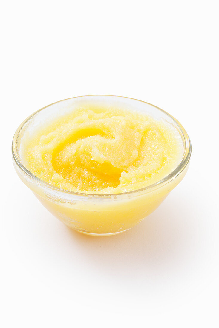 Ghee in a glass bowl on a white surface