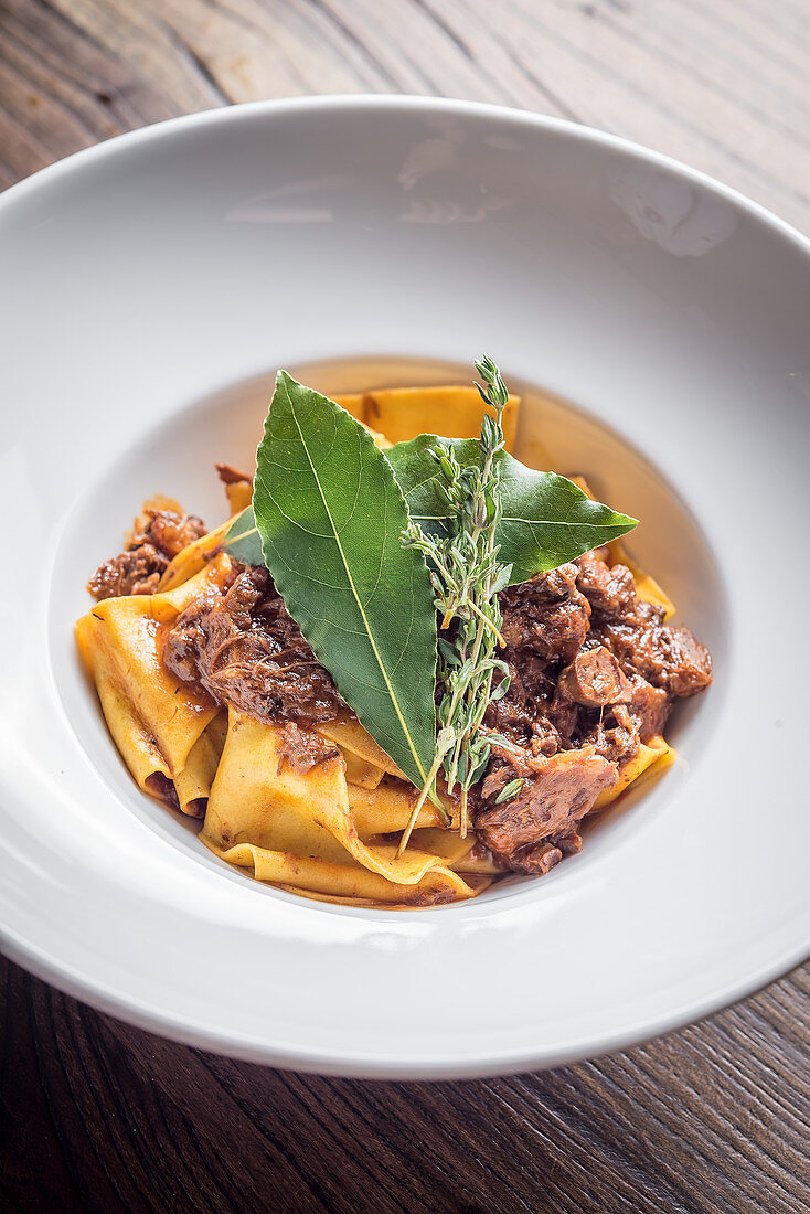 Fresh homemade pappardelle tagliatelle pasta with slow cooked game ragu in red wine and bay leaves garnished with thyme