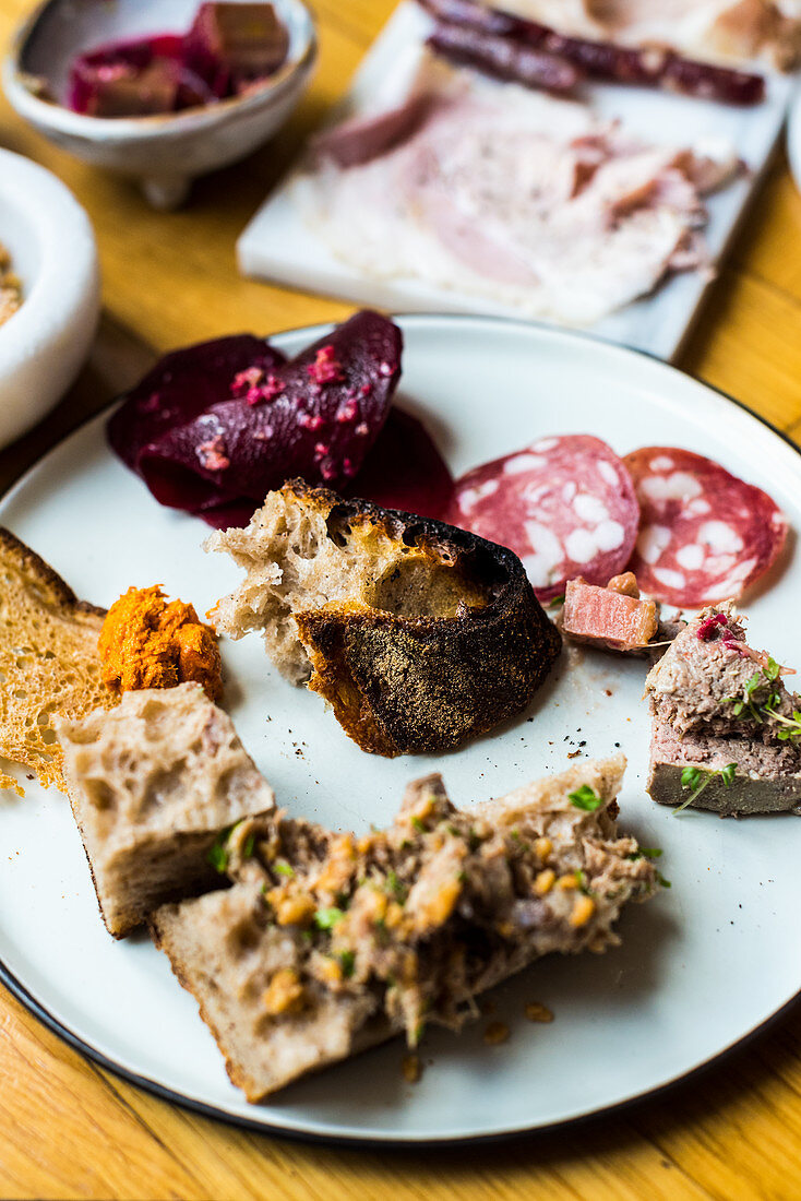 A starter platter with bread, salami, liver pate and vegetable spread