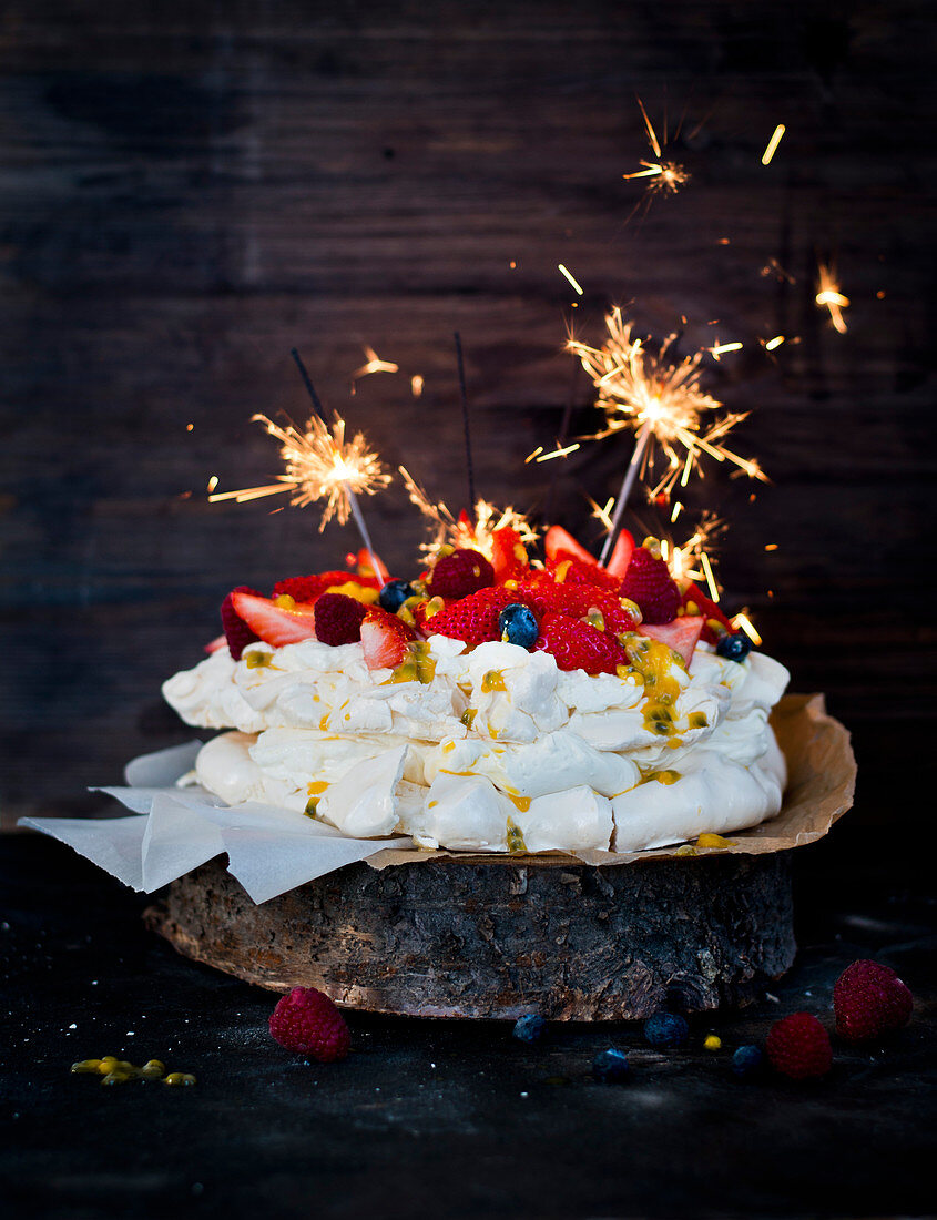 Pavlova with fresh berries, passion fruit sauce and sparklers