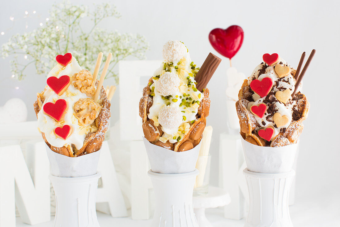 Three different bubble waffles with frozen yoghurt, heart-shaped biscuits and chocolate