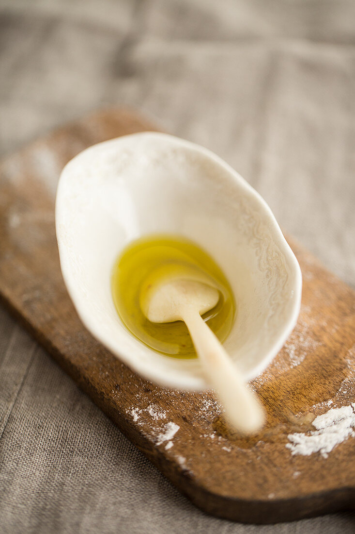 Olivenöl mit Löffel in Porzellanschälchen