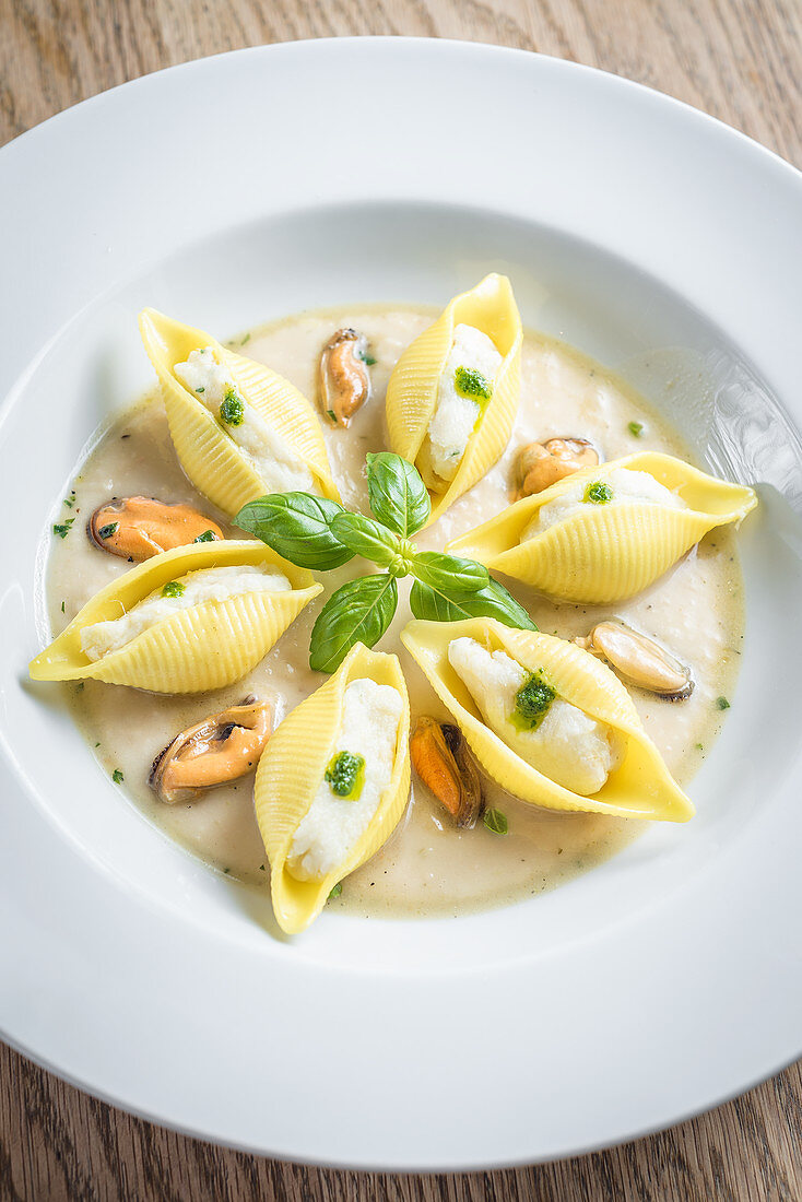 Conchiglioni fresh pasta shells filled with mackerel and ricotta mousse in a creamy white sauce with mussels and pesto sauce