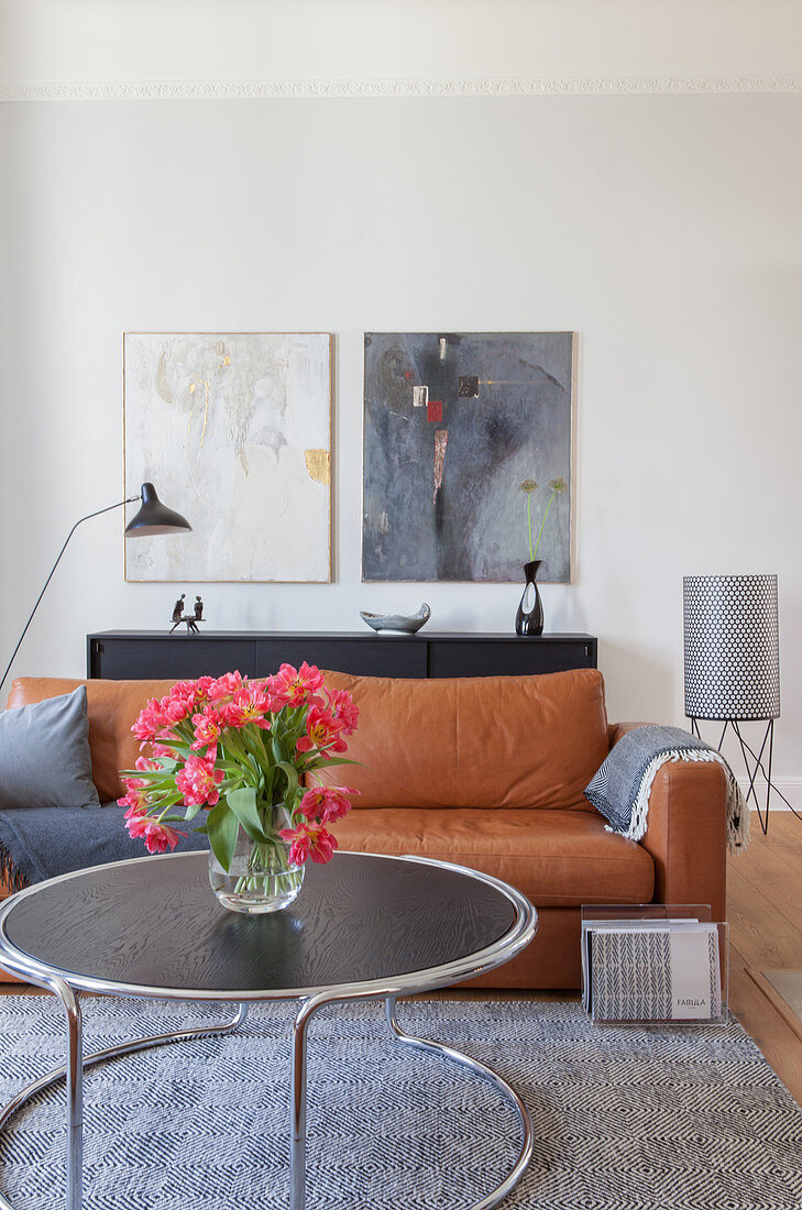 Pink tulips on coffee table in front of cognac-brown leather sofa