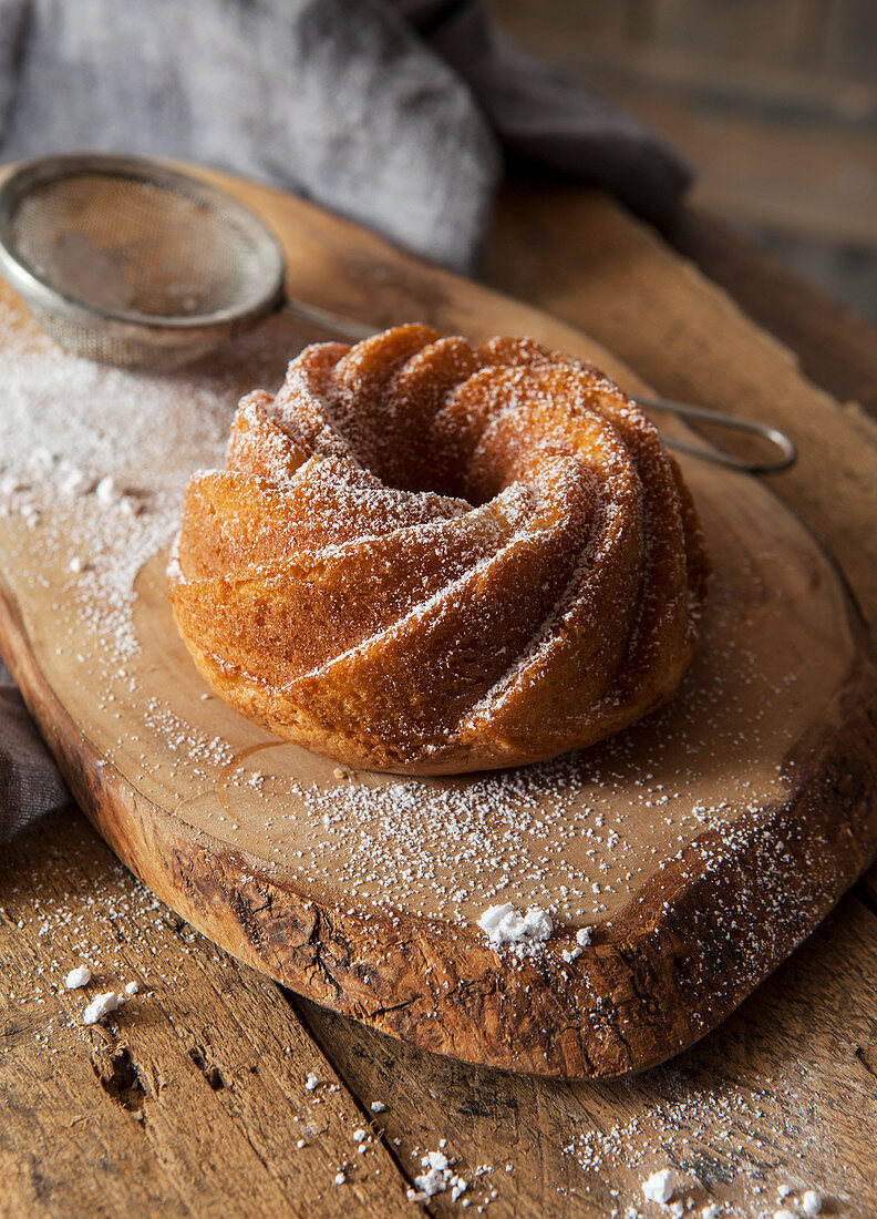A small bundt cake on a rustic wooden board