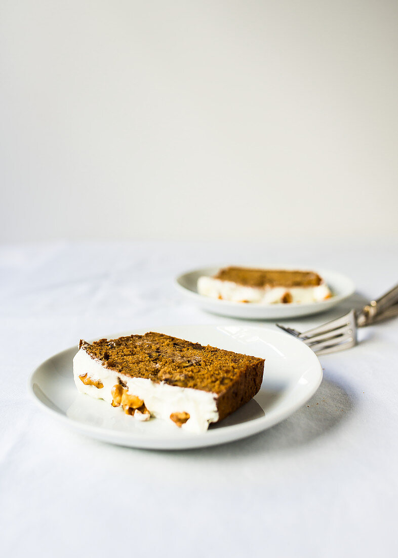 Slices of banana bread with walnuts and icing, on plates