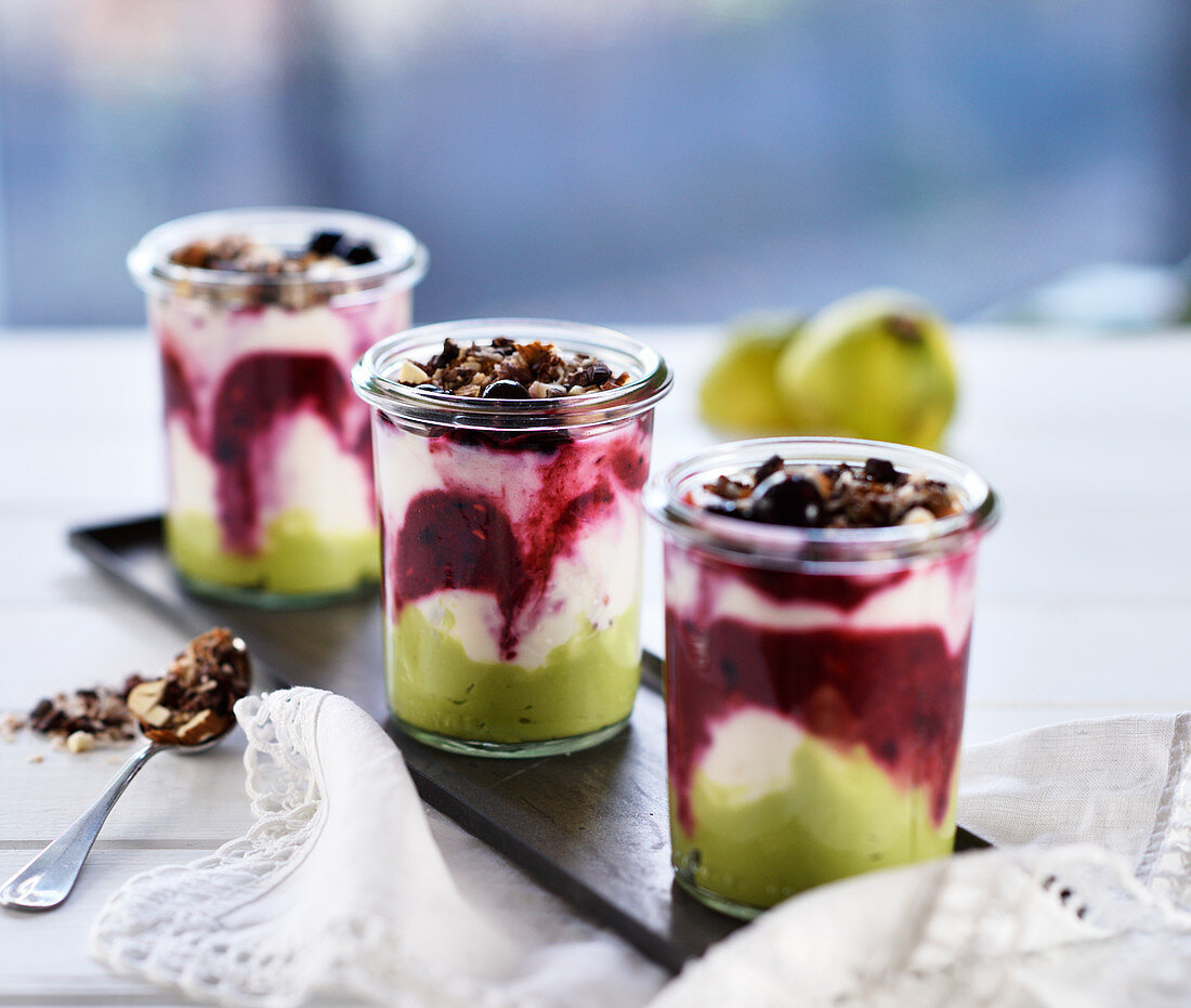 Avocado and lime cream in glasses with wild berries, coconut yoghurt and a crunchy topping (vegan)
