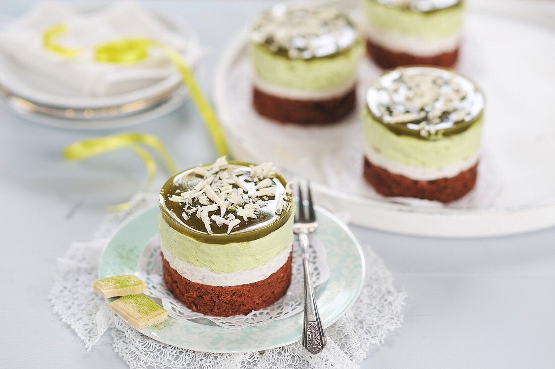 Matcha cream tarts with dark chocolate bases, almond and tonka bean cream, white chocolate and matcha cream, matcha jelly, and grated white chocolate (vegan)