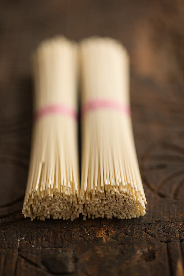 Two bundles of udon noodles on a wooden background