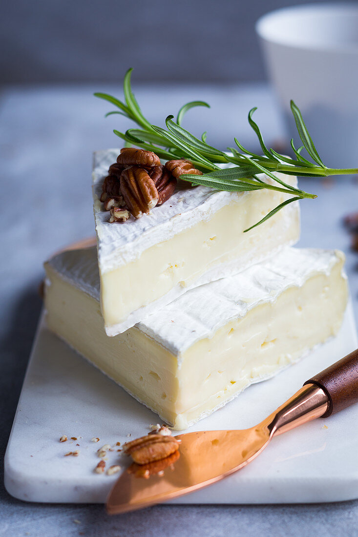 Zwei Stücke Brie Käse mit Nüssen und Rosmarin