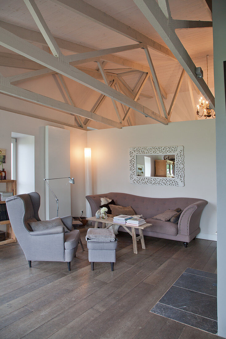 Comfortable sofa set against half-height partition in converted stable with exposed wooden roof structure