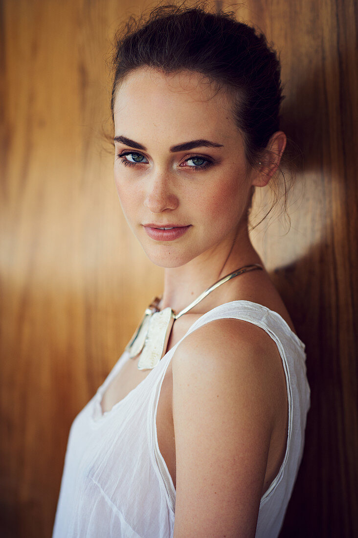 A young brunette woman wearing a white top and a chunky necklace