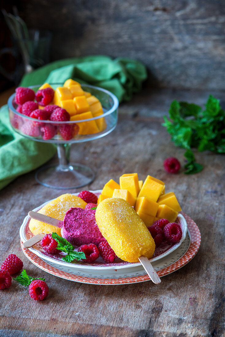 Mango and raspberry ice lollies served with fresh fruit
