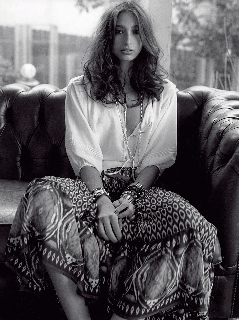 A young, long-haired woman wearing a patterned skirt with a white blouse (black-and-white shot)