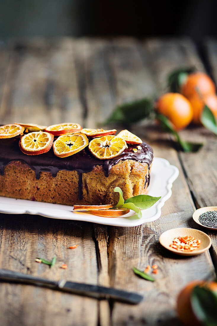 Tangerine loaf cake with chocolate glaze on rustic wooden table