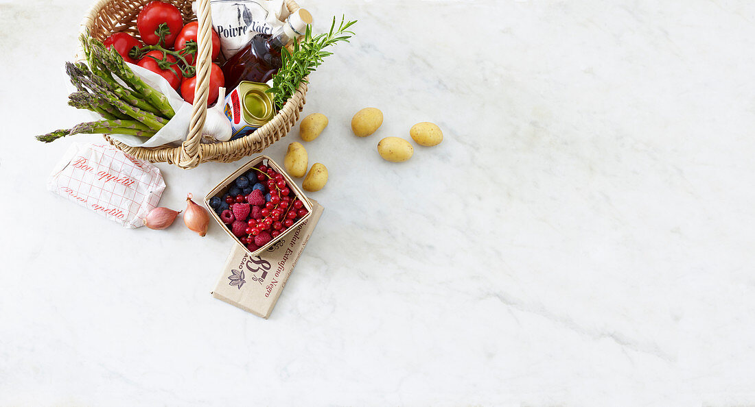 Fresh fruit, vegetables, herbs, and vinegar in a shopping basket