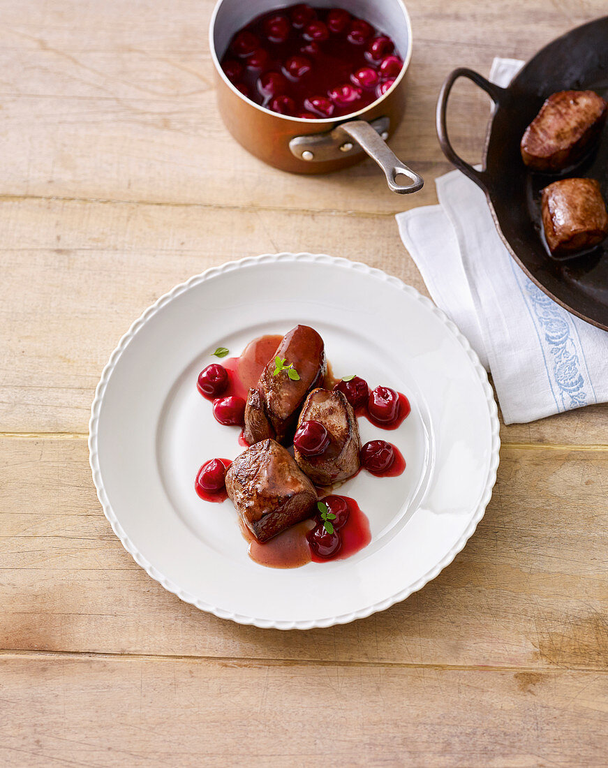 Venison medallions in licorice sauce with marinated cherries