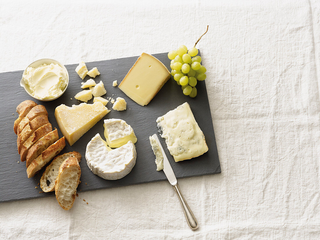 A cheese plate with grapes and a fresh baguette