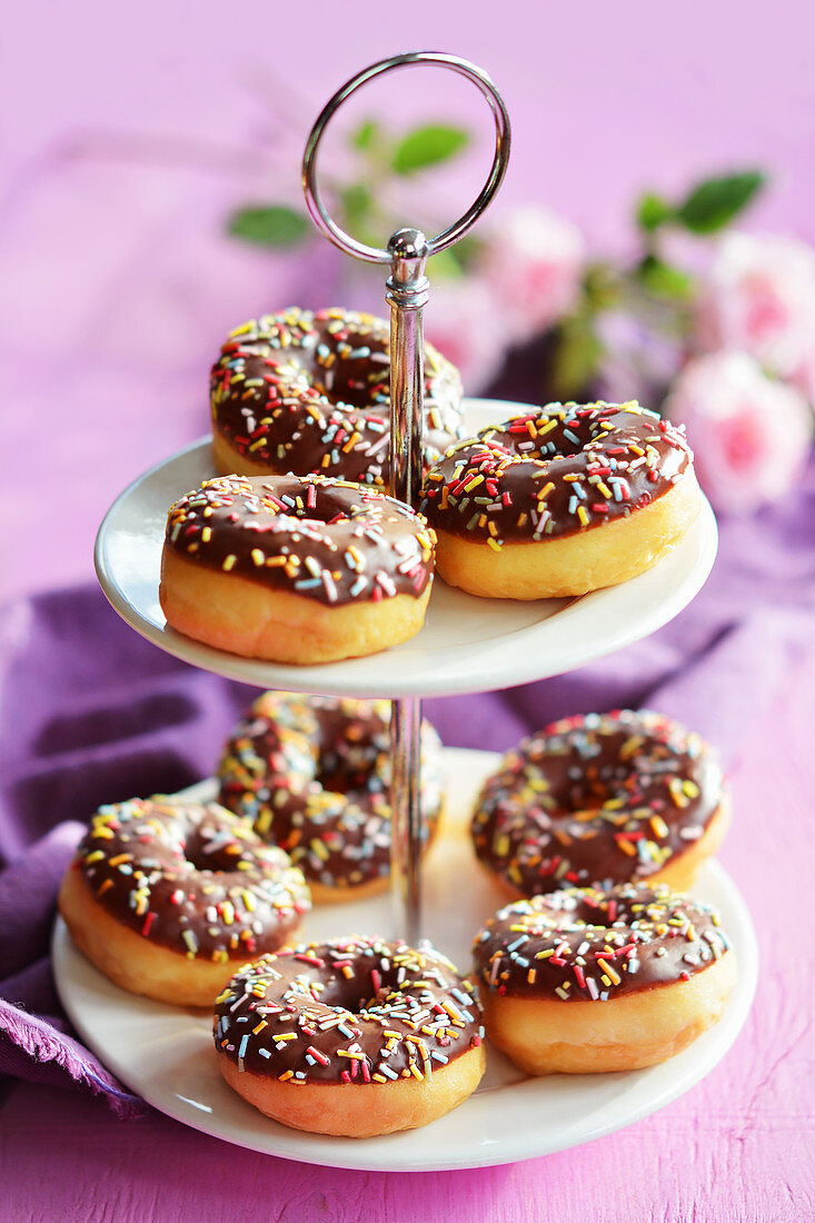 Mini-Donuts mit Schokoladenglasur und Zuckerstreuseln auf Etagere