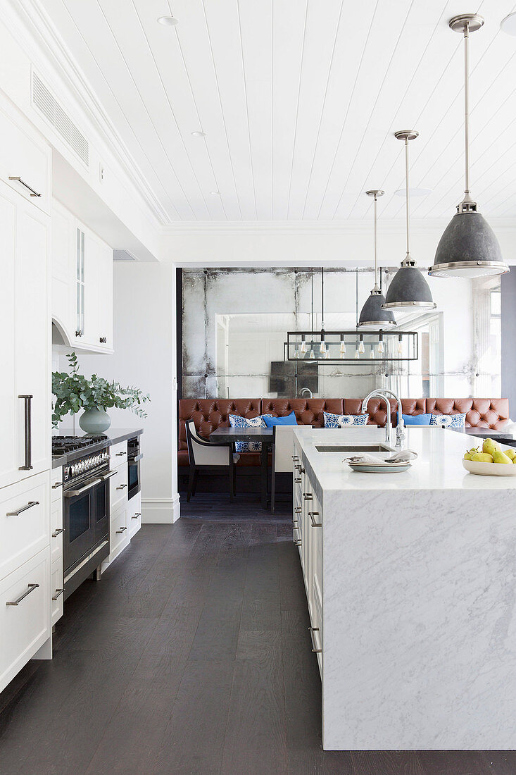 Kitchenette and marble kitchen island under pedal lights in an open living room