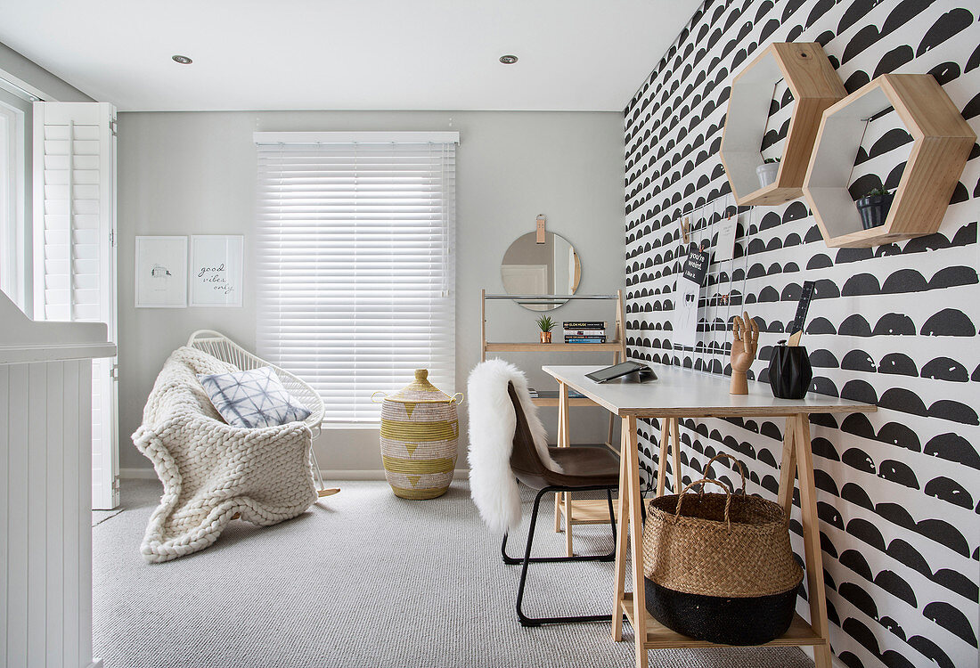 Black and white wallpaper, desk, chair and blanket on armchair in study