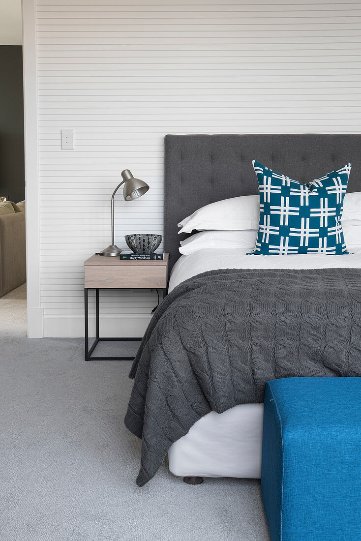 Double bed and bedside table against finely striped wallpaper in bedroom