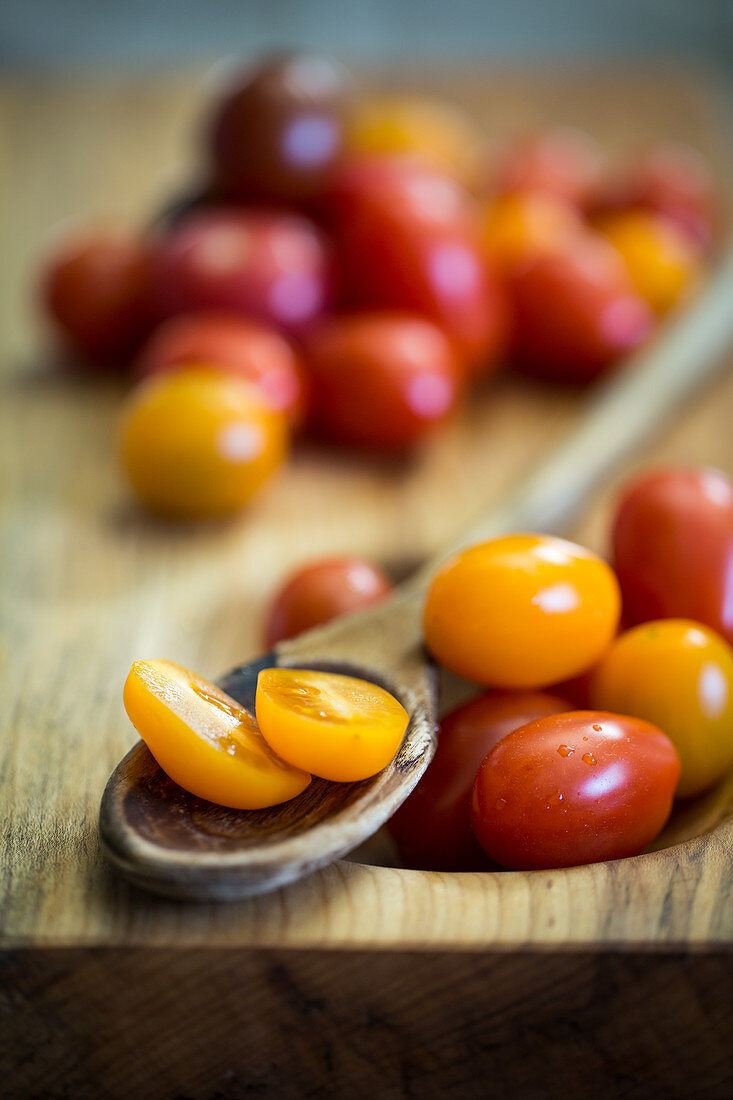 Cherry tomatoes on a wooden board and a wooden spoon
