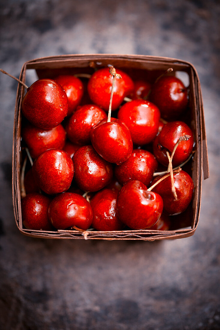 Fresh cherries in a wooden basket (seen from above)