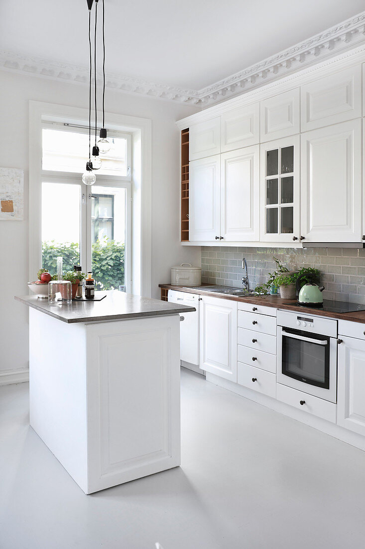 weiße Landhausküche mit Kücheninsel und Stuckdecke