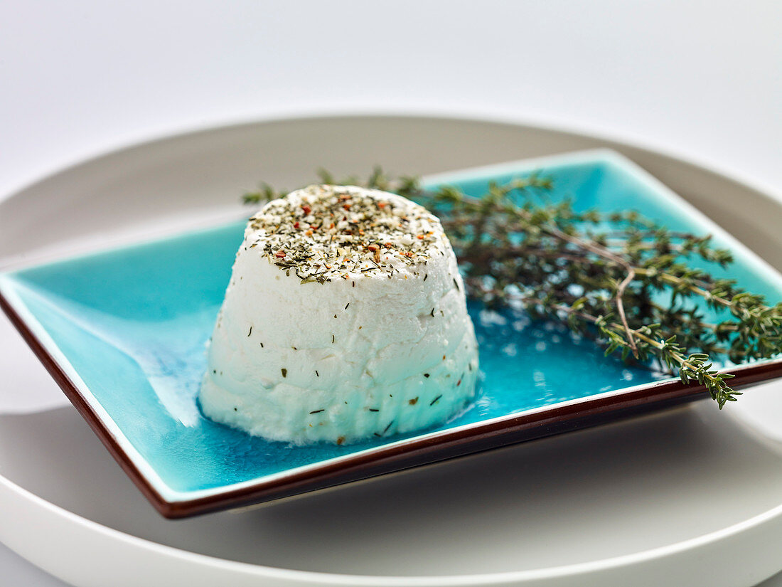 Fresh goat's cheese with herbs on a blue plate