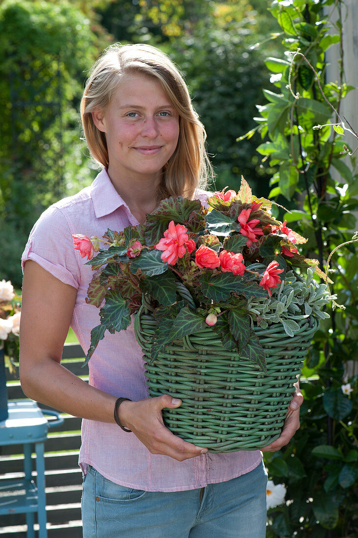 Frau trägt Korb mit Begonia Iconia 'Miss Malibu'