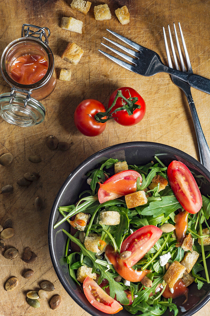Salad with rocket, tomatoes, pumpkin seeds, croutons, feta chees and tomatoe dressing