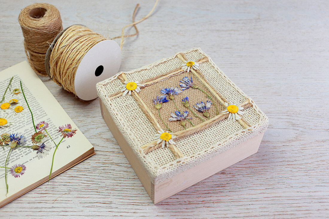 Schachtel mit gepressten Blüten und Band verzieren