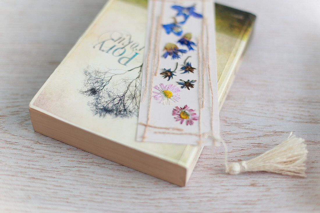 Bookmark decorated with pressed flowers, threads and tassel