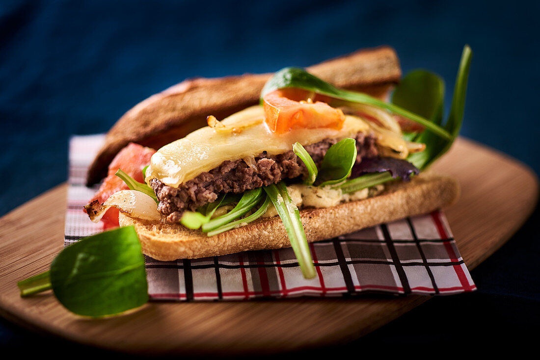 A sandwich with minced meat, cheese and lambs lettuce