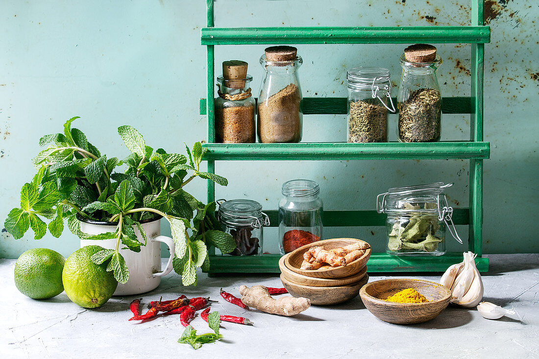 Kitchen table with variety of spices, fresh mint and limes