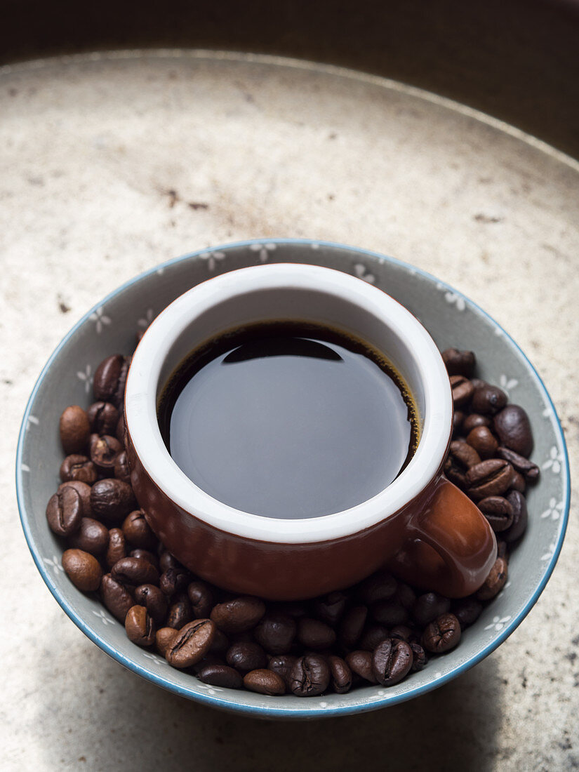 Kaffeebohnen in Schüssel mit einer Tasse Espresso