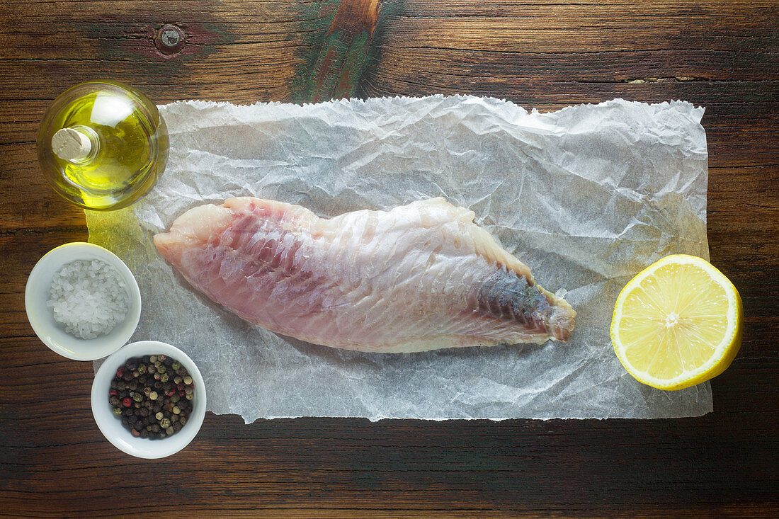 Raw red snapper with ingredients on a wooden surface