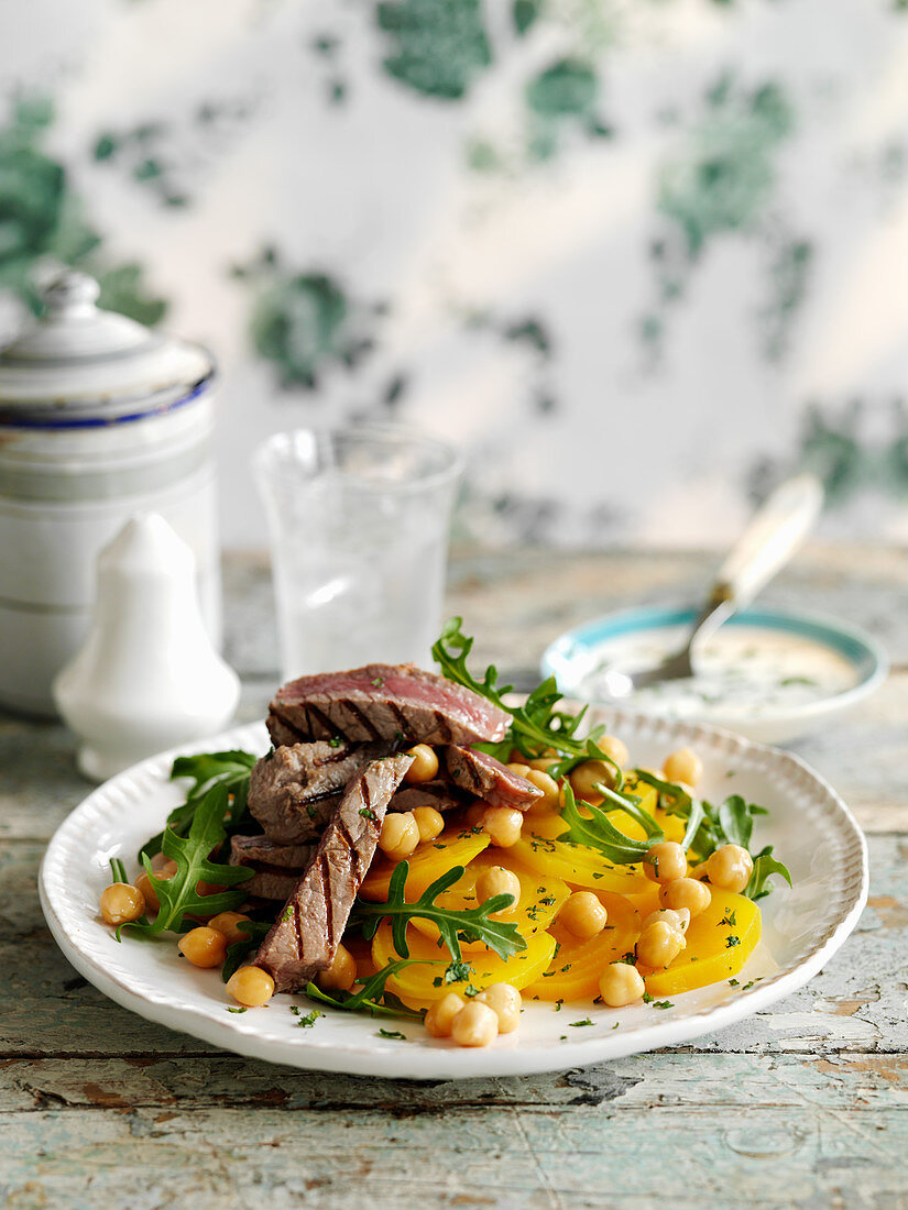 Grilled steak slices with yellow beetroot, chickpeas, and rocket