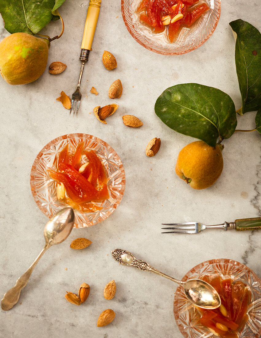 A still life of quince, almonds, old forks, spoons and crystal bowls