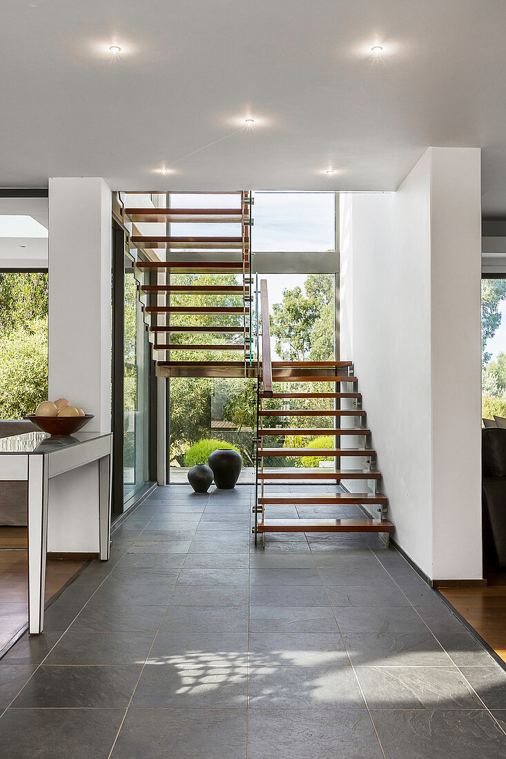 Modern free-standing staircase in front of glass wall overlooking garden