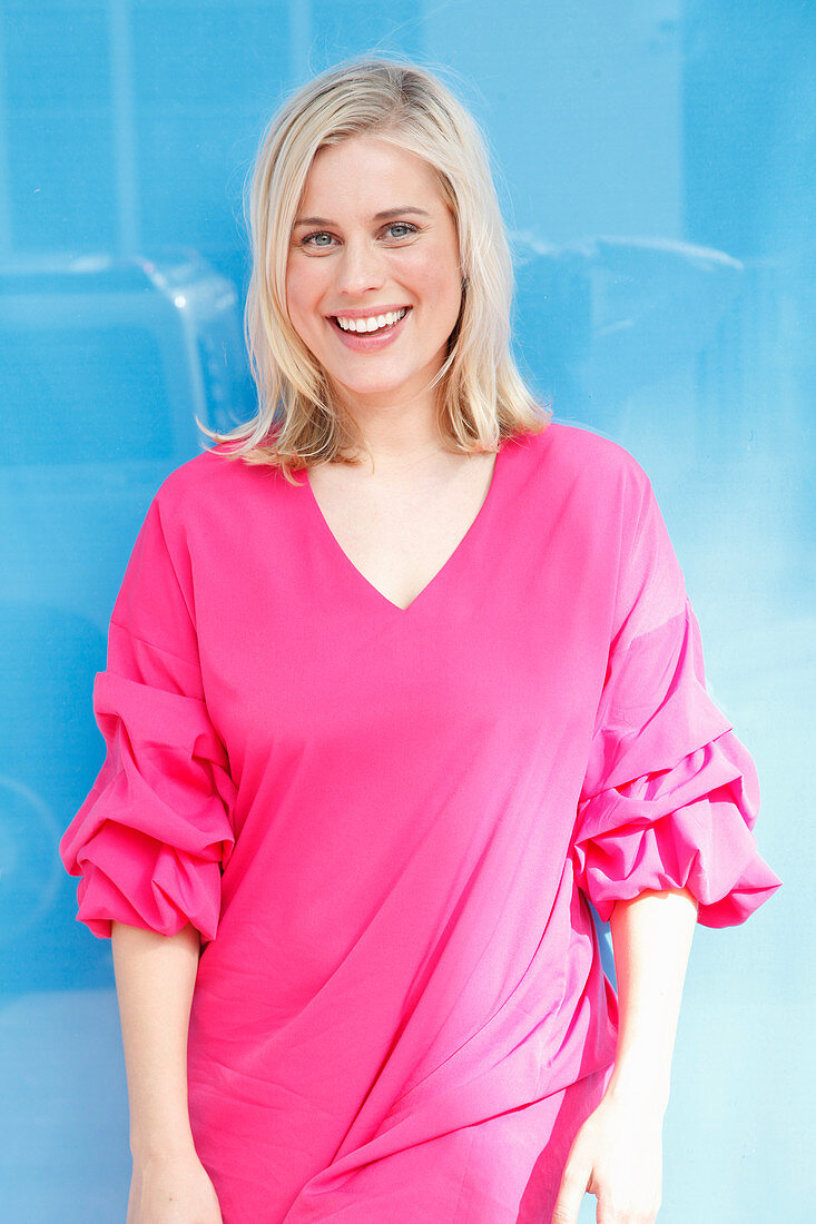 A young blonde woman wearing a long pink top