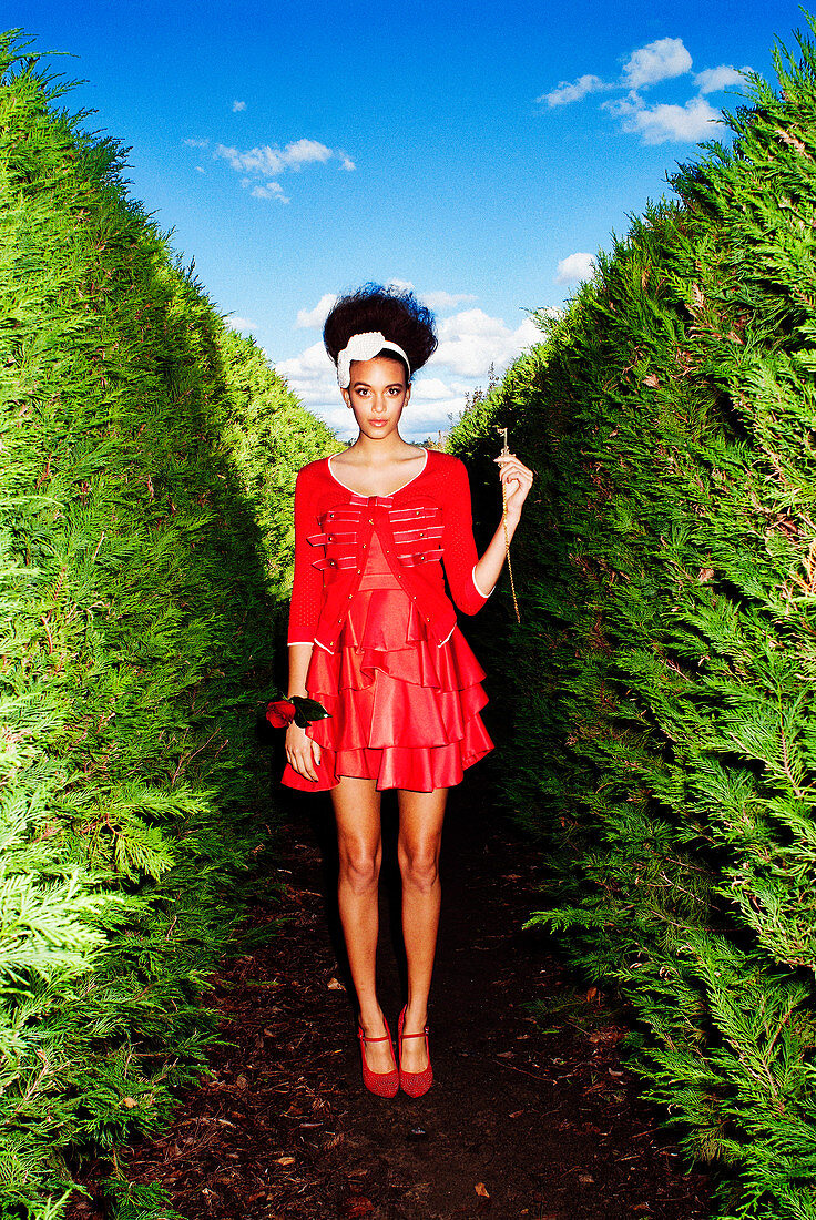 A young woman in a park wearing a red dress and a jacket