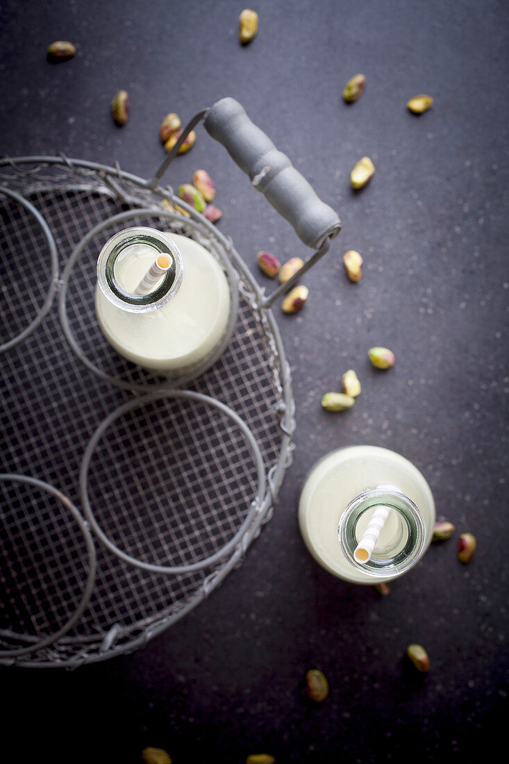 Selbstgemachte Pistazienmilch mit Strohhalmen in Flaschen (Aufsicht)