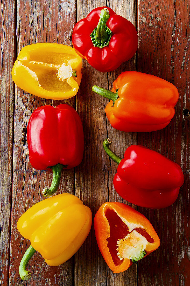 Red, yellow and orange peppers on a wooden background