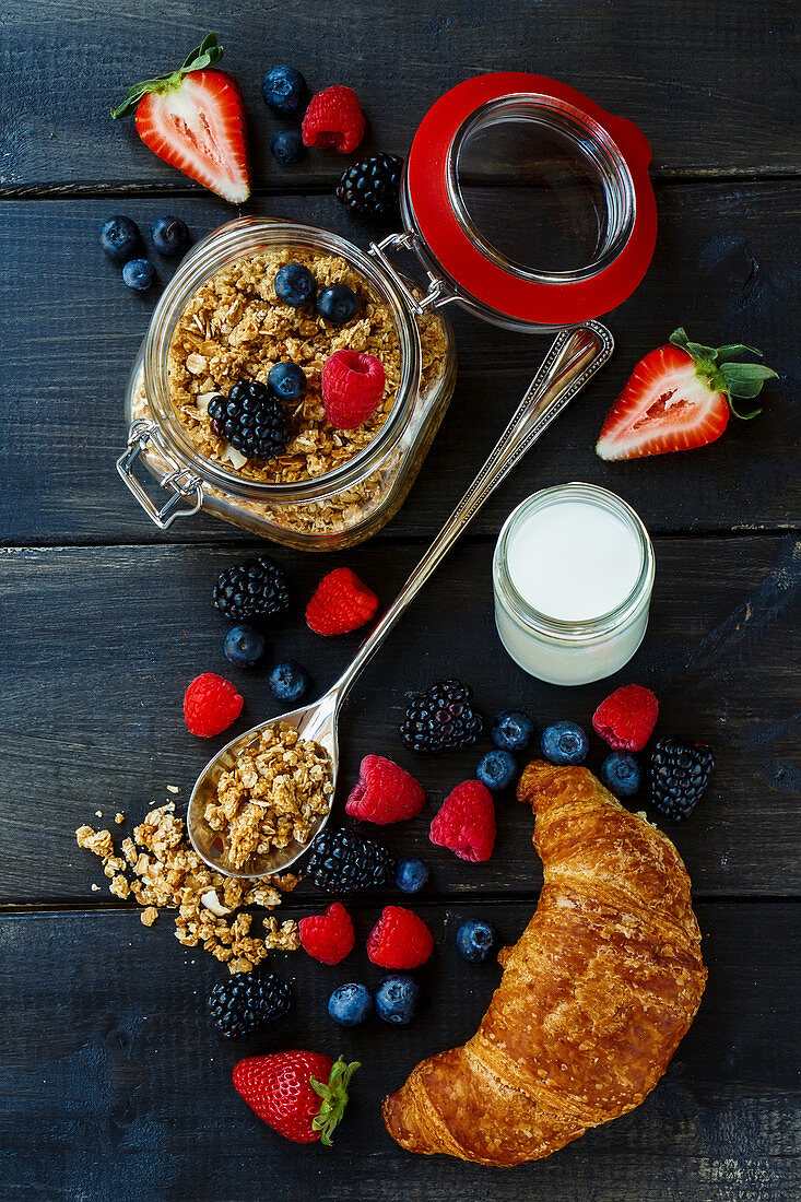 Frühstückszutaten: Müsli, Beeren, Joghurt und Croissant (Aufsicht)