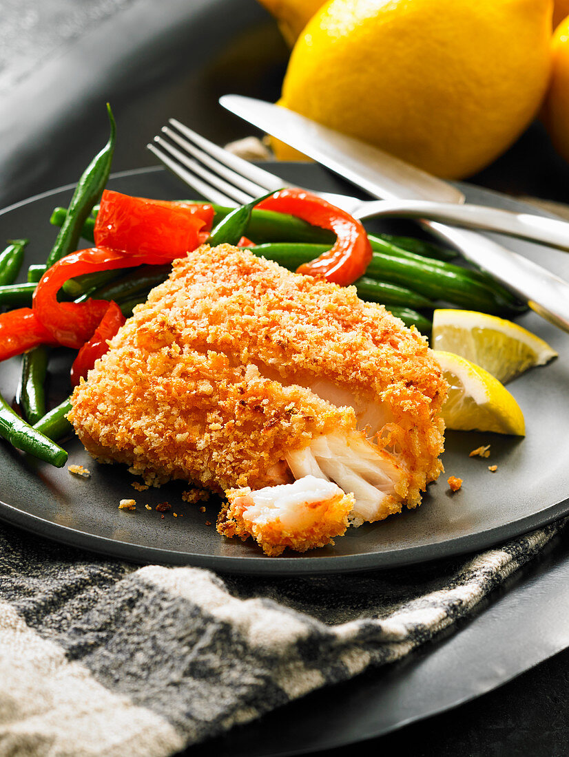 A cod fillet in a panko crust with green beans and peppers